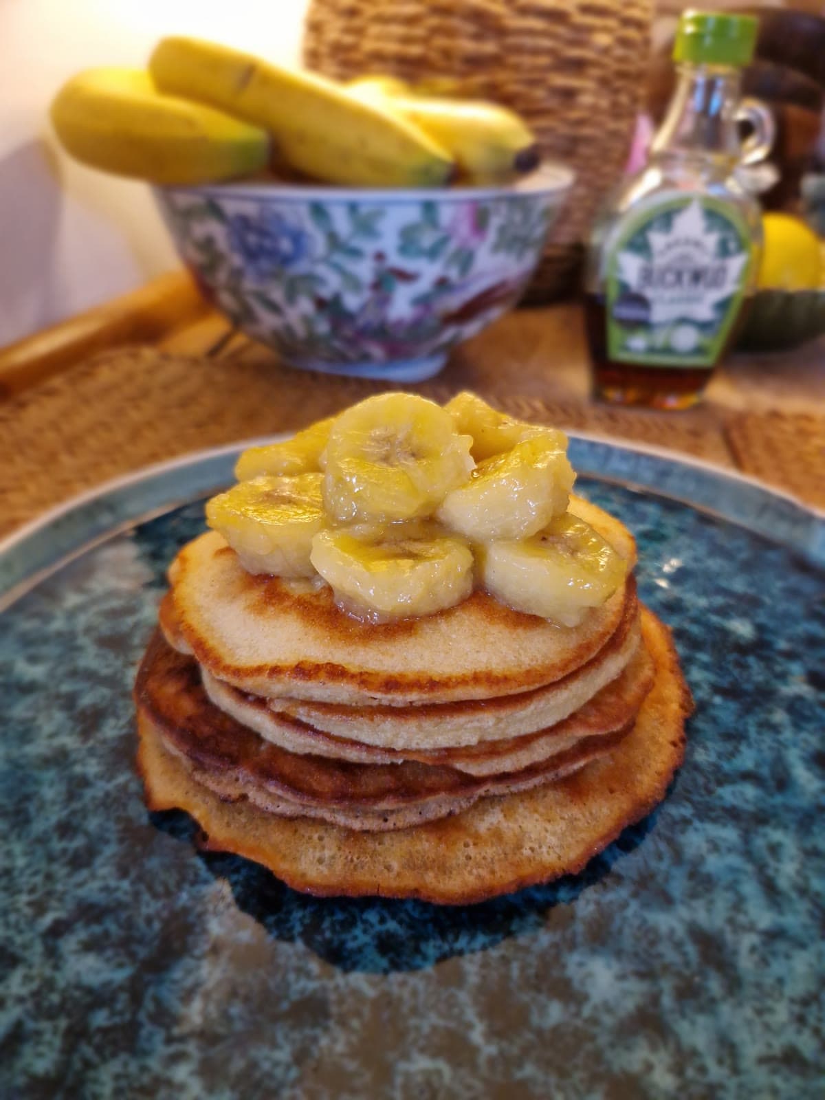 A stack of pancakes topped with caramelized banana slices on a blue plate