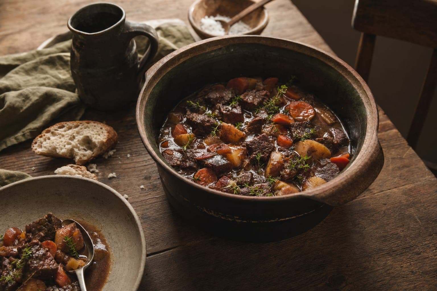 A skillet of slow-cooked beef stew on a rustic stove in warm light