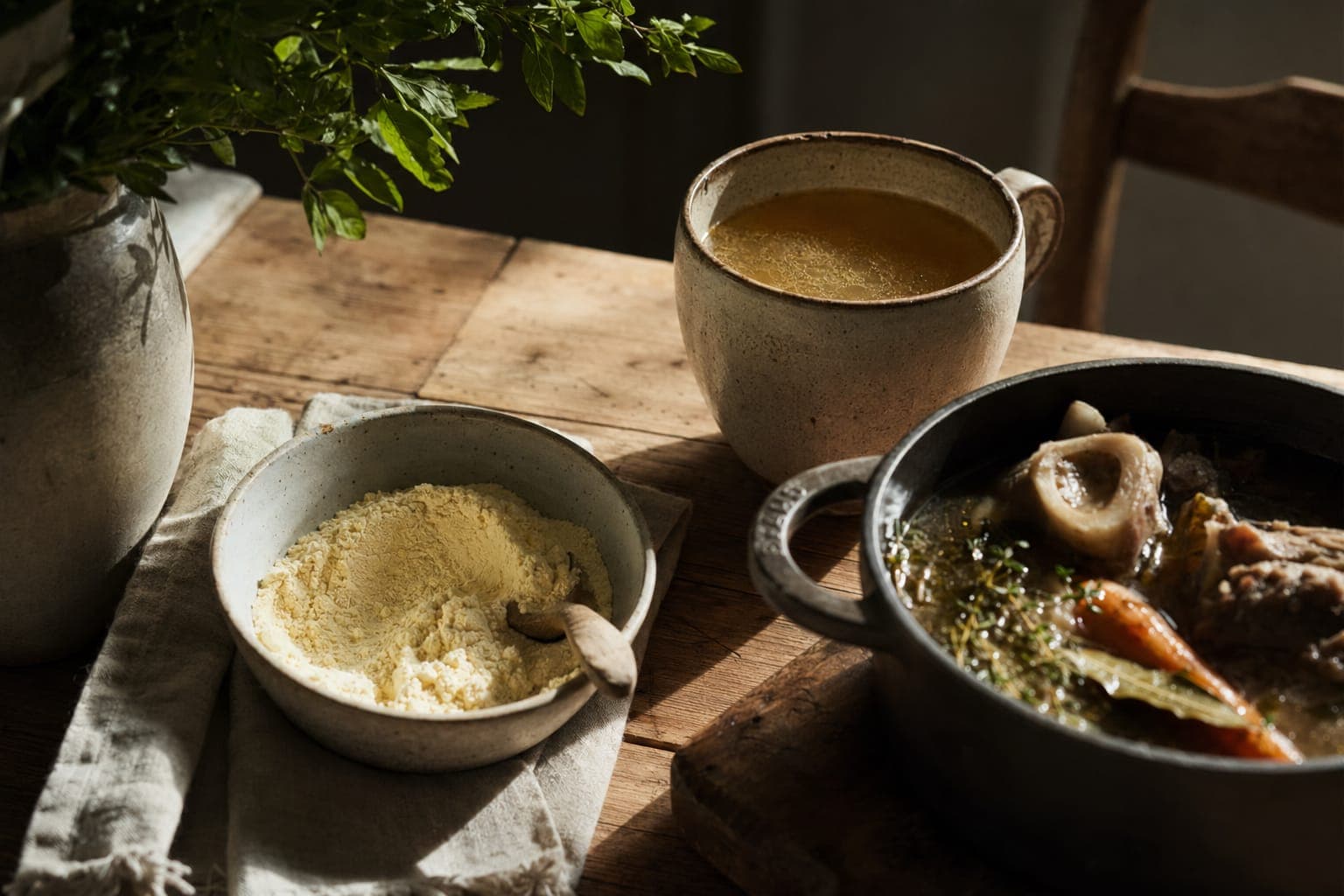 A bowl of broth with bread on a rustic table in warm light