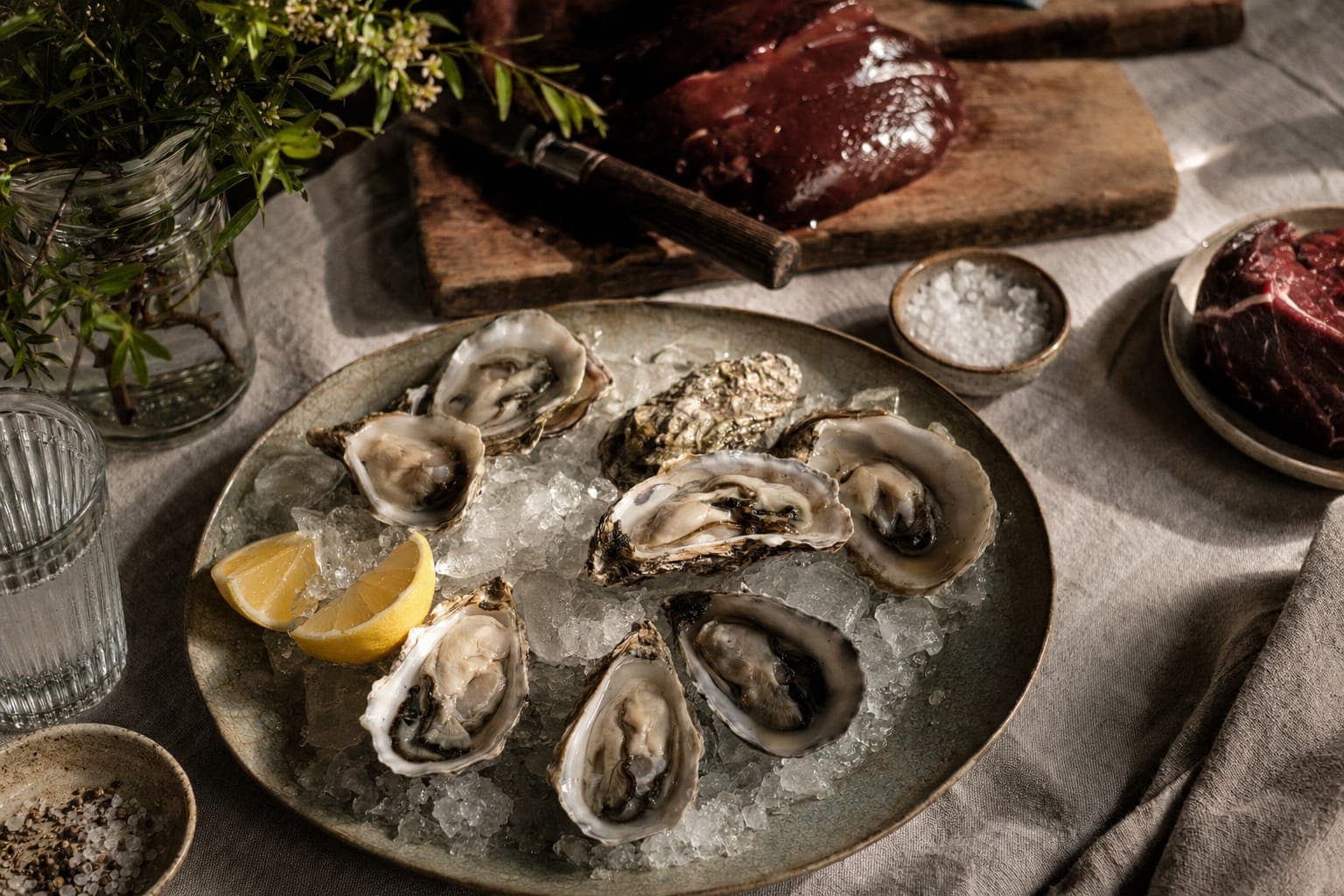 A board of fresh oysters and shellfish on a rustic table
