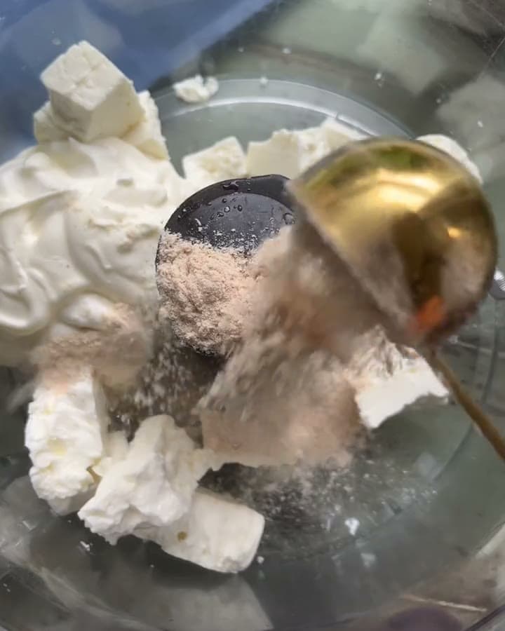 Olive oil pouring over feta and the blend, ready to whip into a dip