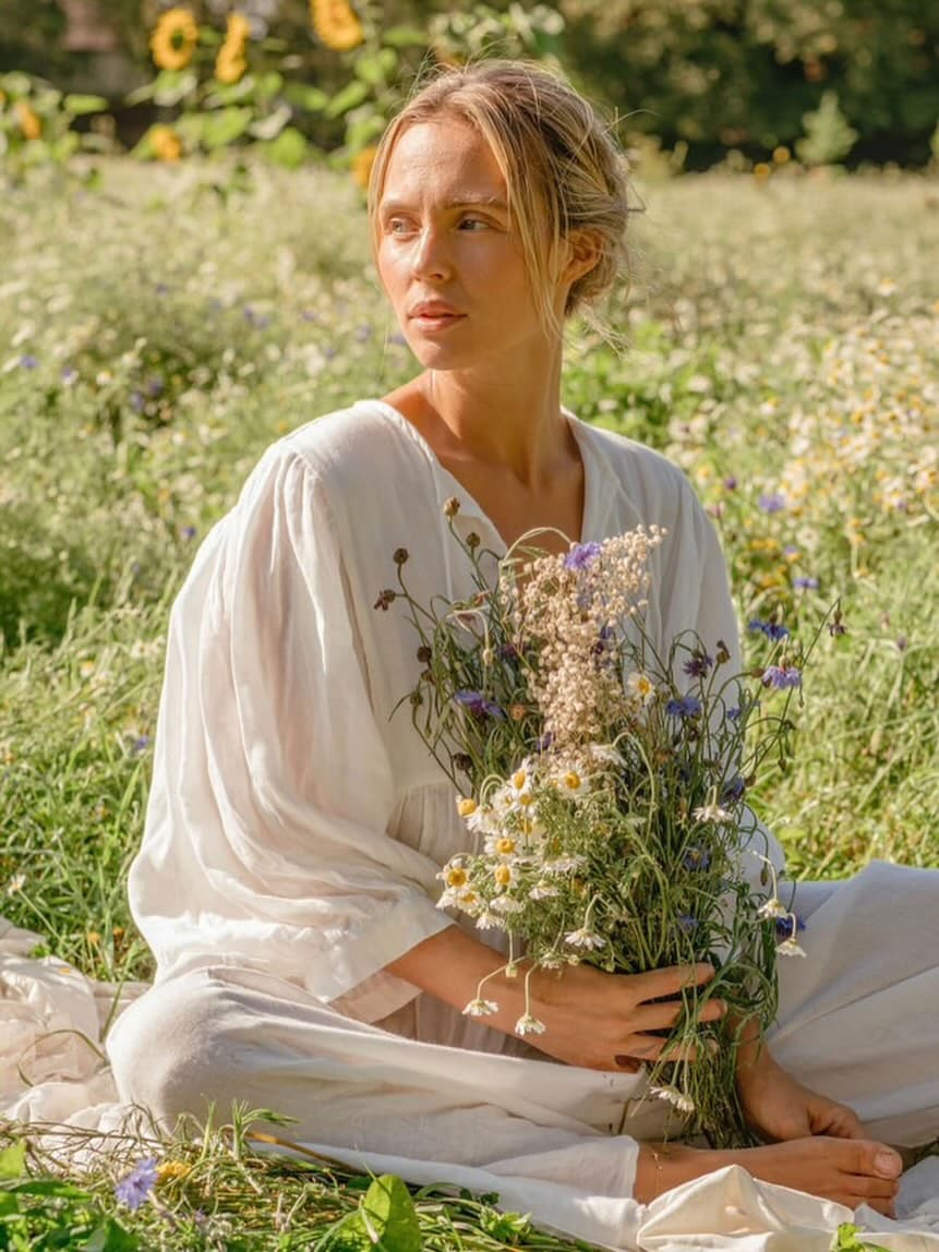 Ruby + Glow sitting in a wildflower meadow with a bunch of fresh flowers