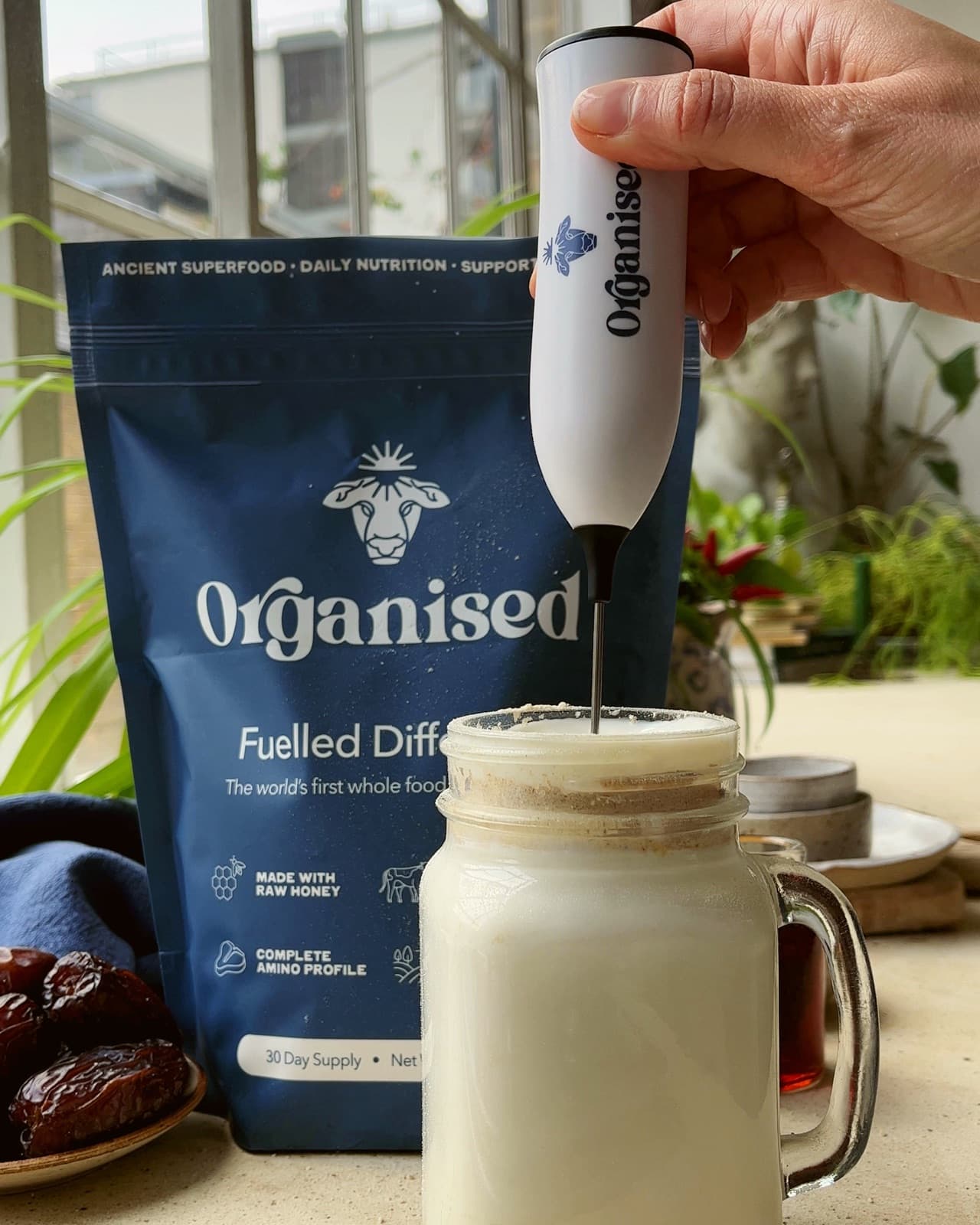 Frothing a glass of milk with Organised, dates and honey beside the pouch