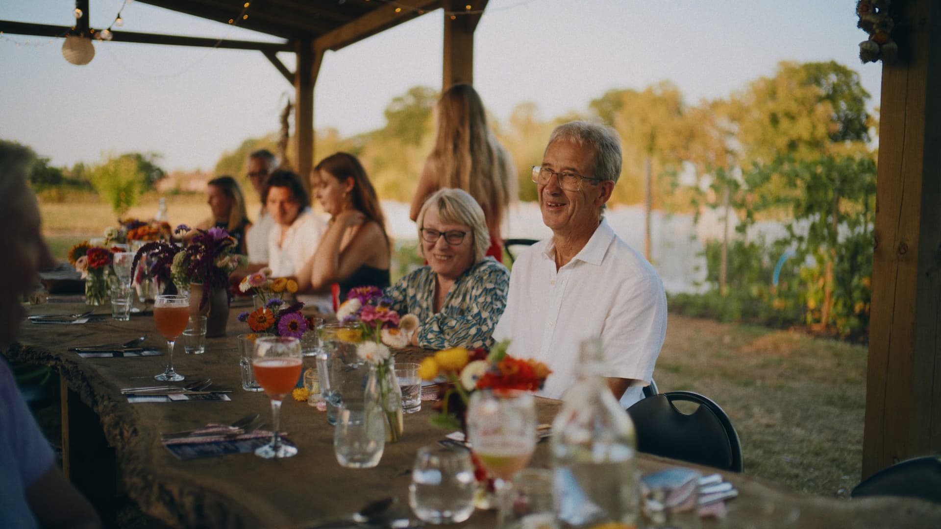 Guests laughing together at the long table as the light goes golden