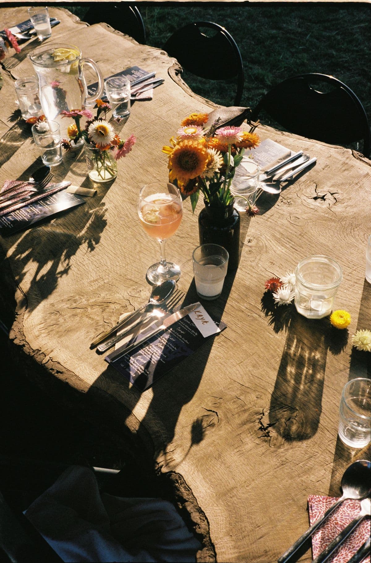 The table plainly laid, flowers and glasses in the evening sun