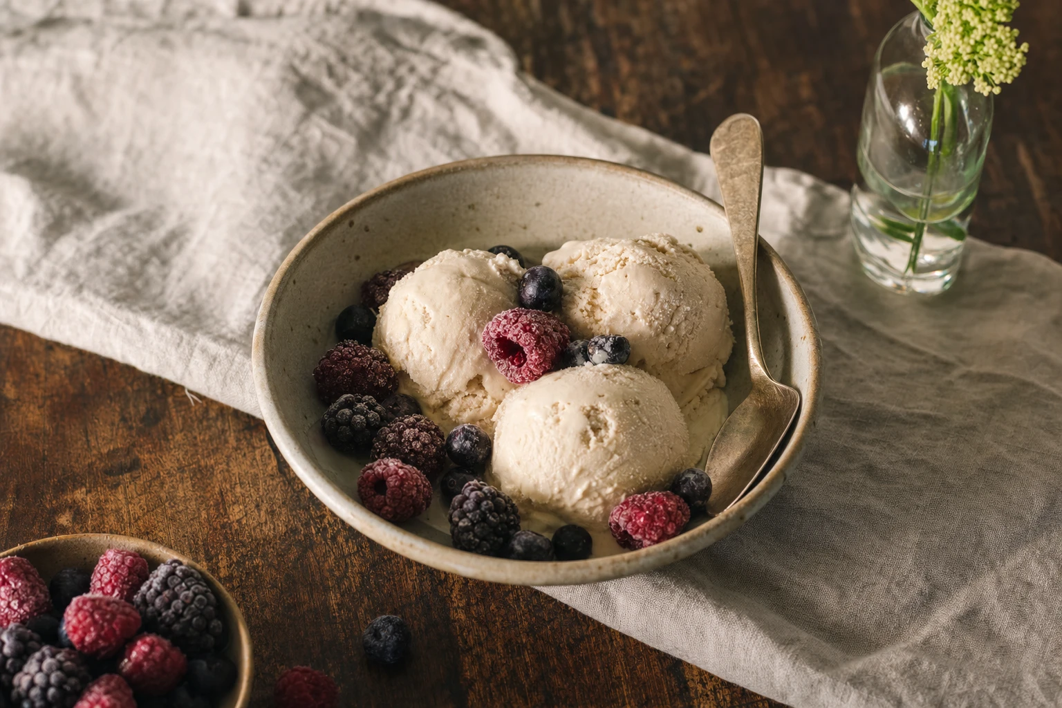 Scoops of creamy frozen dessert in a bowl, garnished with fresh berries