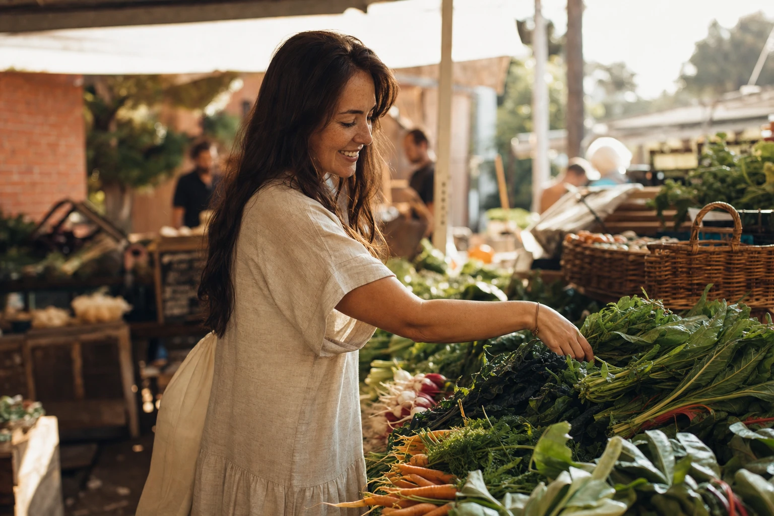 A person shopping in a farmer's market, smiling, surrounded by fresh produce