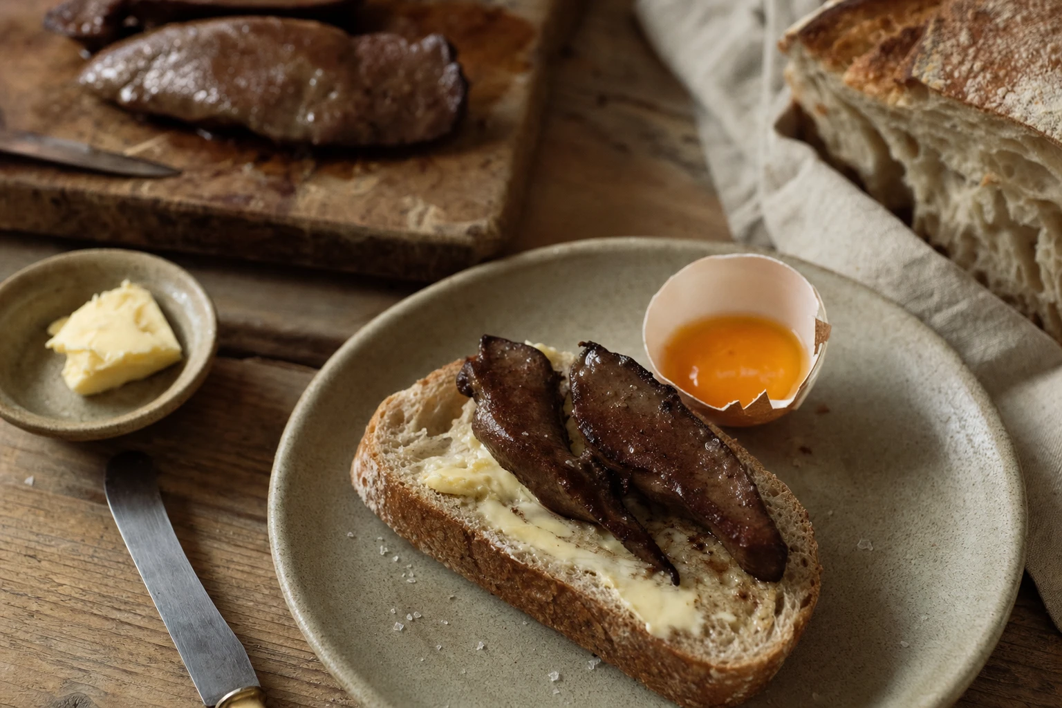 Plate with liver, egg yolk, butter on artisanal bread